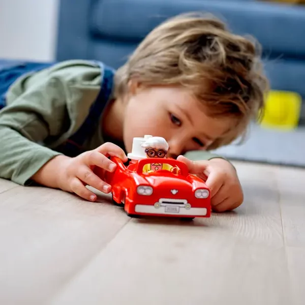 Wnuczek trzymający samochód z zestawu LEGO® DUPLO® Parking piętrowy i myjnia samochodowa