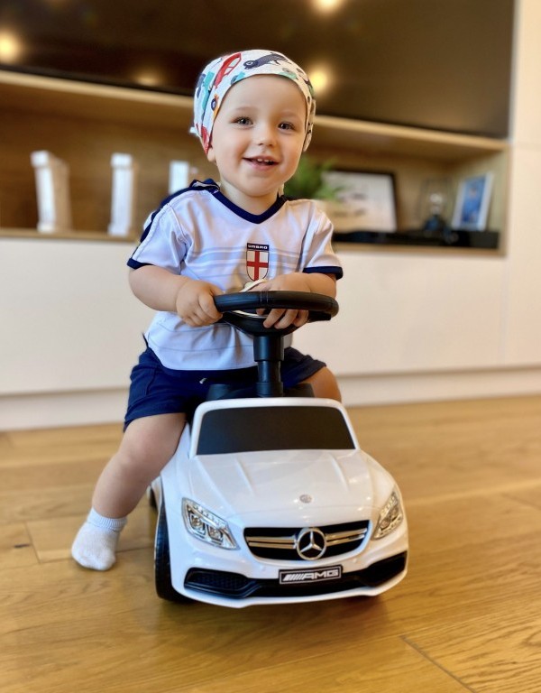 trzyletni chłopiec na białym jeździku Mercedes