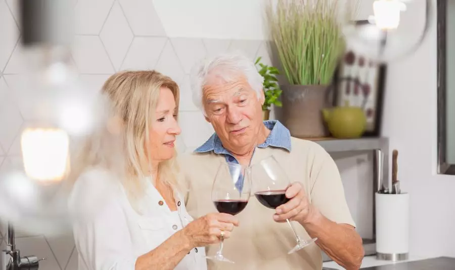 Czy można pić alkohol po zawale? Na zdjęciu para seniorów pije wino.