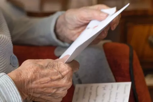 Starsza pani czyta list do seniora.