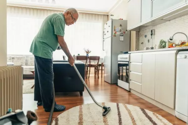 Mężczyzna wykorzystuje lekki odkurzacz dla seniora podczas sprzątania.