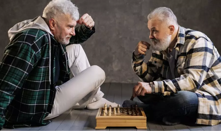Gry dla seniorów, takie jak szachy, w które grają mężczyźni na zdjęciu, skutecznie poprawiają pamięć i koncentrację.