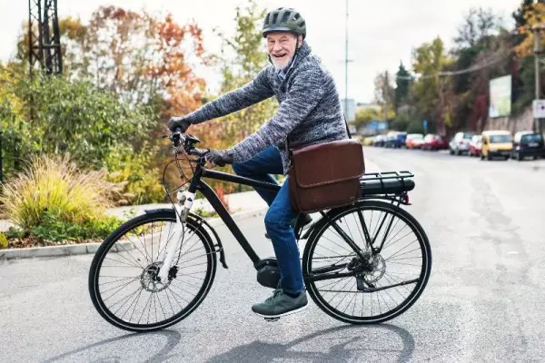 Szczęśliwy starszy mężczyzna i jego lekki rower elektryczny dla seniora.