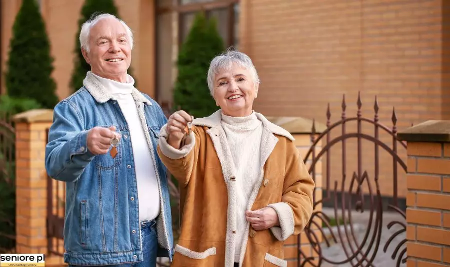 Małżeństwo seniorów trzyma klucze do mieszkania na osiedlu dla seniorów.