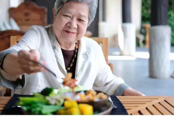 Kobieta spożywa danie, które zakłada dieta keto dla seniora.