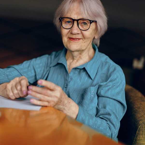 seniorka siedząca przy stole nad dokumentami