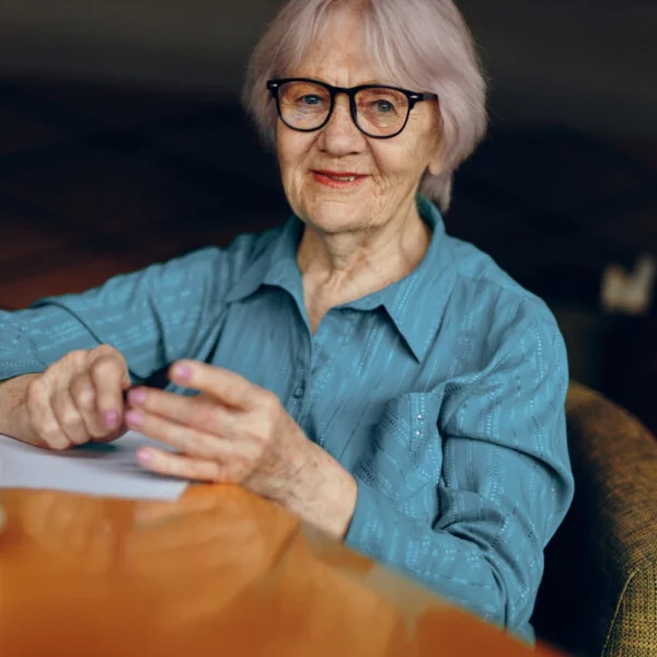 seniorka siedząca przy stole nad dokumentami