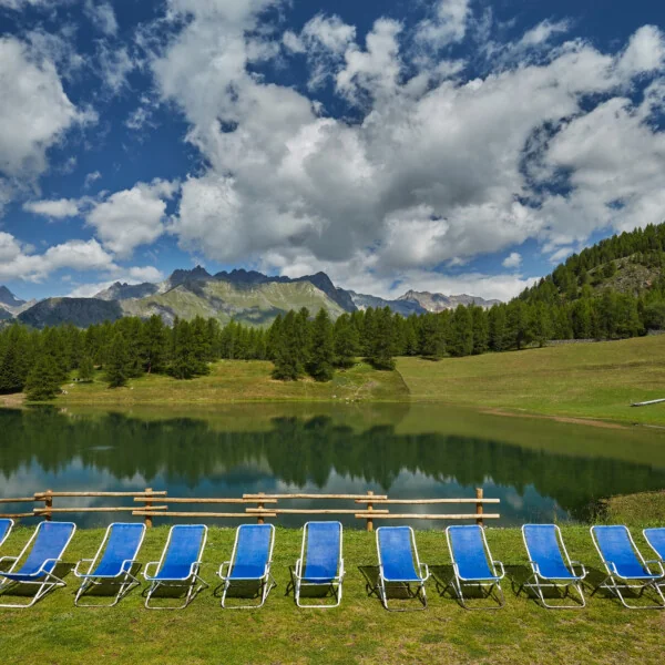 Leżaki stojące przy jeziorze w otoczeniu gór i lasów - relaks w uzdrowisku