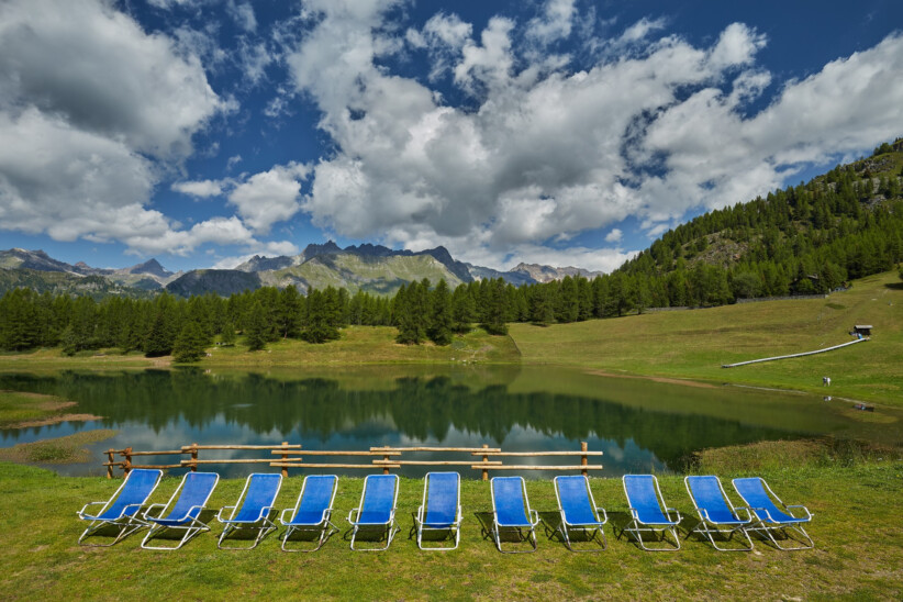 Leżaki stojące przy jeziorze w otoczeniu gór i lasów - relaks w uzdrowisku