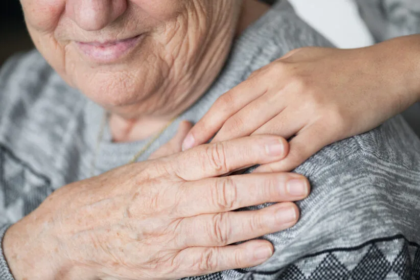 Dłoń opiekuna trzymająca rękę seniorki – wsparcie i opieka nad osobą starszą