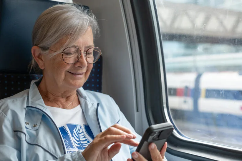 seniorka w pociągu, przegląda telefon, siedząc 