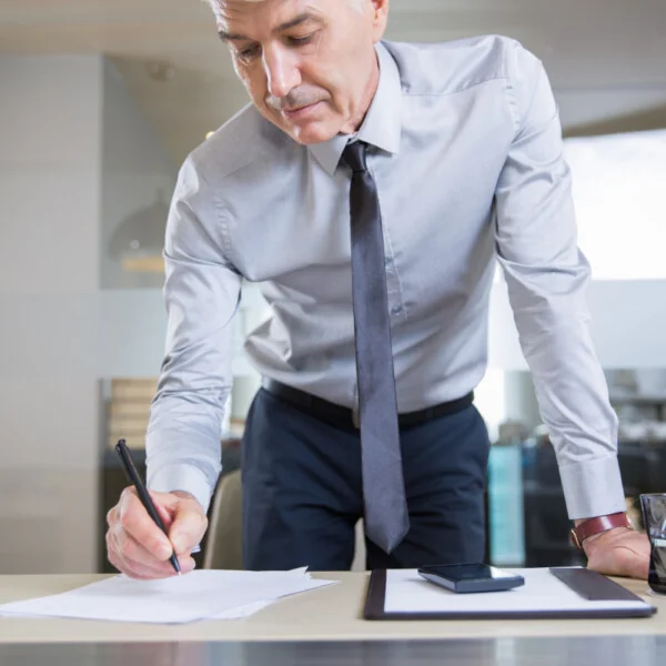 mężczyzna podpisujący dokument przy biurku – sporządzanie testamentu lub umowy darowizny