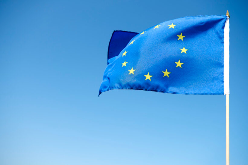 Flaga Unii Europejskiej na tle błękitnego nieba – przepisy dotyczące emerytury zagranicznej w UE