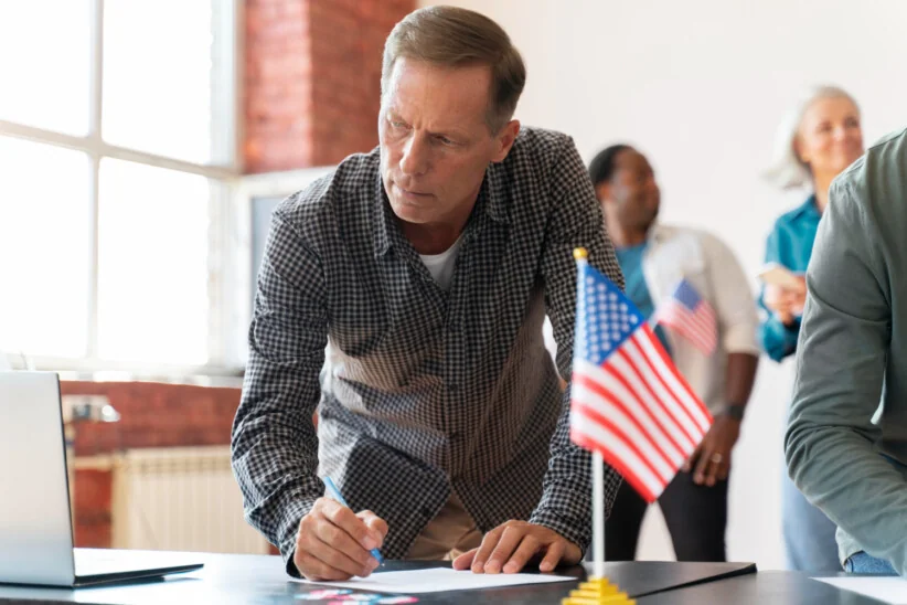 Mężczyzna podpisujący dokumenty przy amerykańskiej fladze – formalności związane z emeryturą i pracą w USA