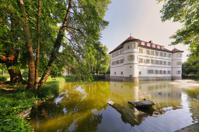 Sanatorium otoczone wodą i zielenią w słoneczny dzień