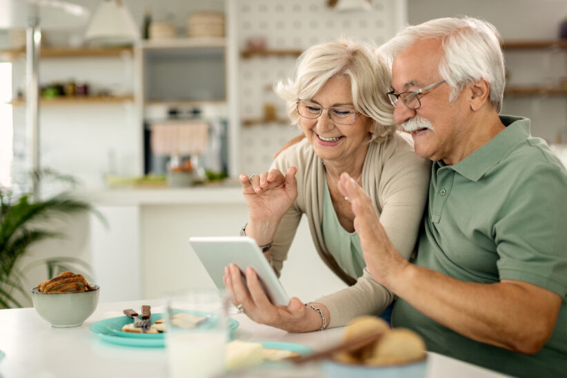 Seniorzy rozmawiający przez wideorozmowę na tablecie w domu