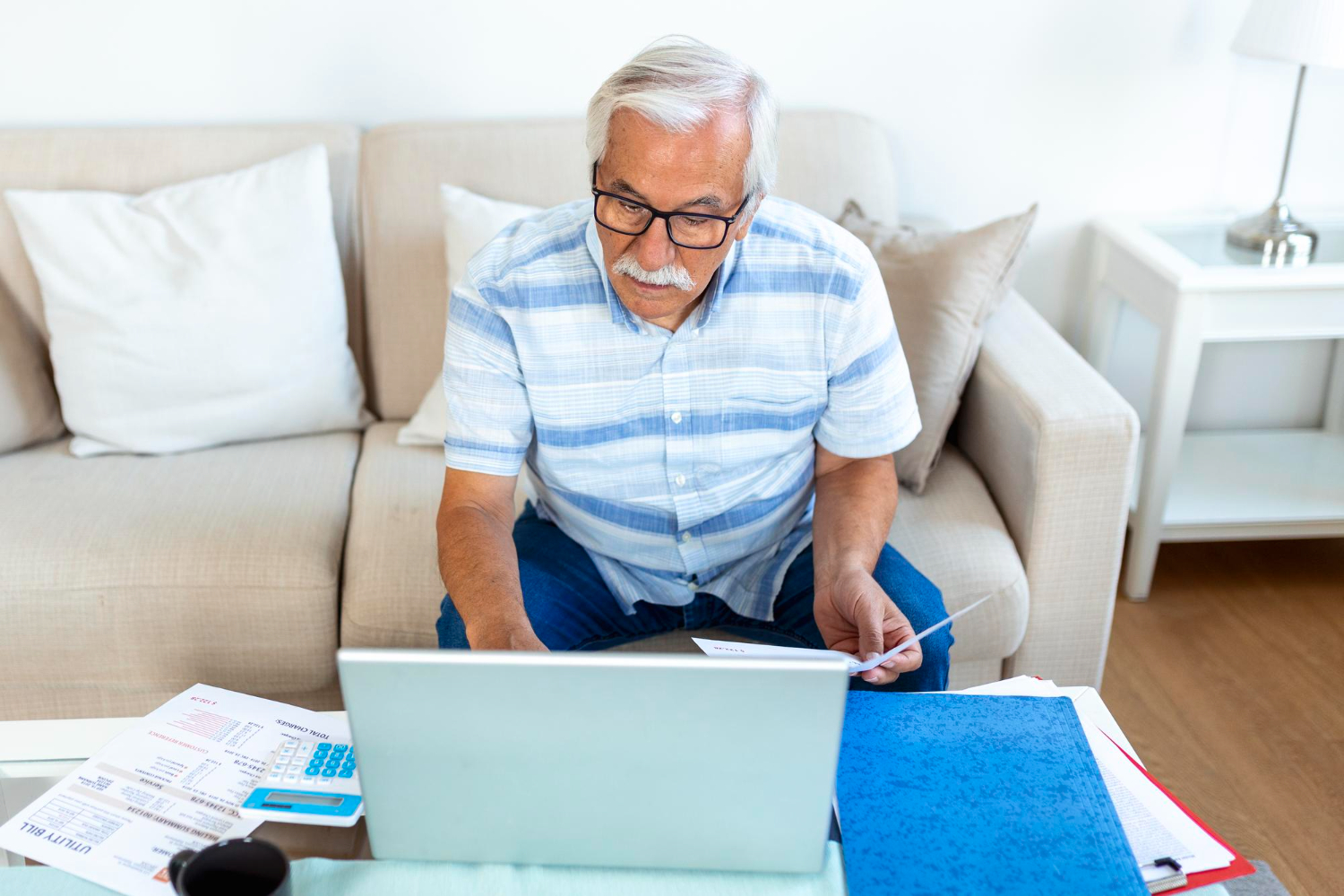 senior na kanapie szuka czegoś w laptopie