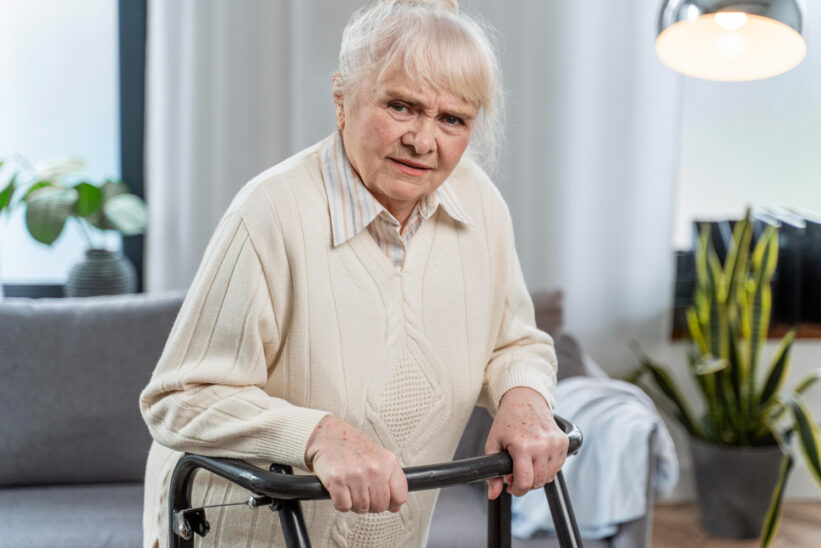 Seniorka korzystająca z chodzika w domowym wnętrzu