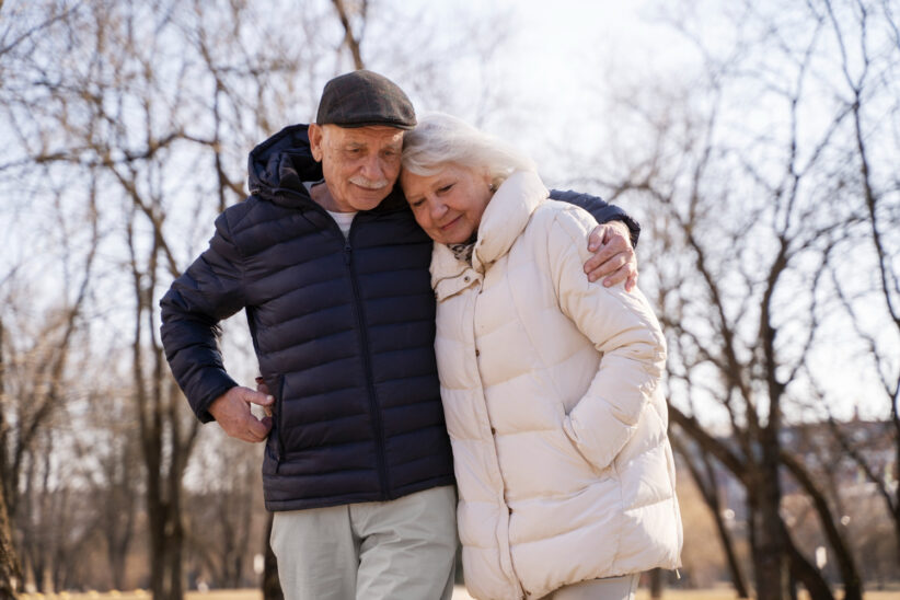 Seniorzy w zimowych kurtkach żegnający się ze sobą przed wyjazdem do sanatorium