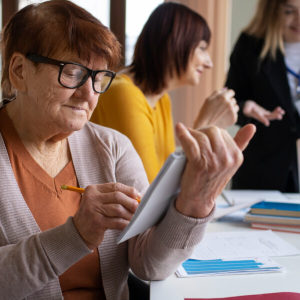 Seniorka wypełnia dokumenty podczas wizyty w urzędzie