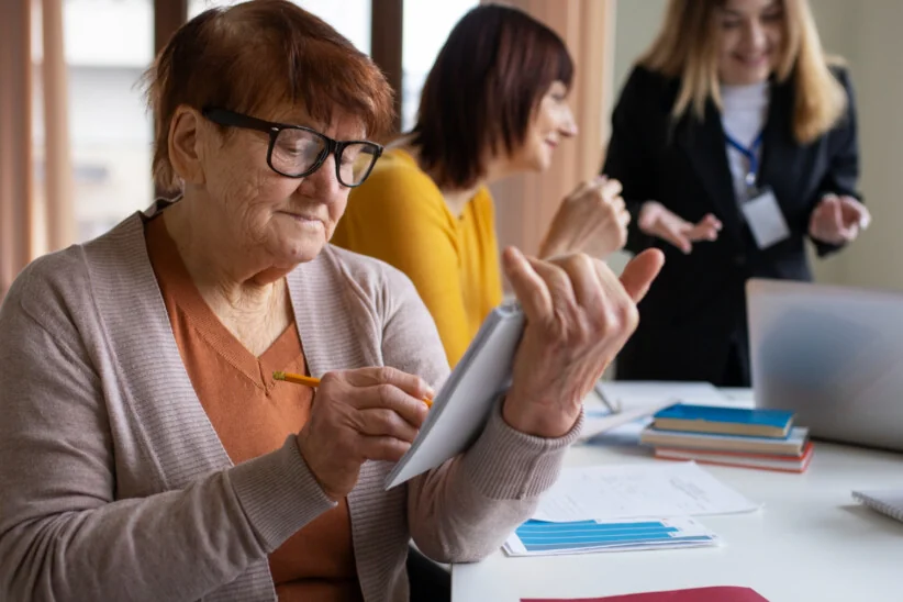 Seniorka wypełnia dokumenty podczas wizyty w urzędzie