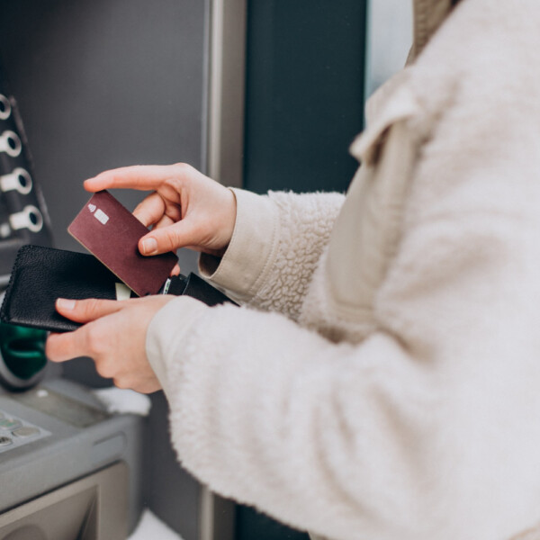 Osoba wypłacająca pieniądze z bankomatu przy użyciu karty płatniczej