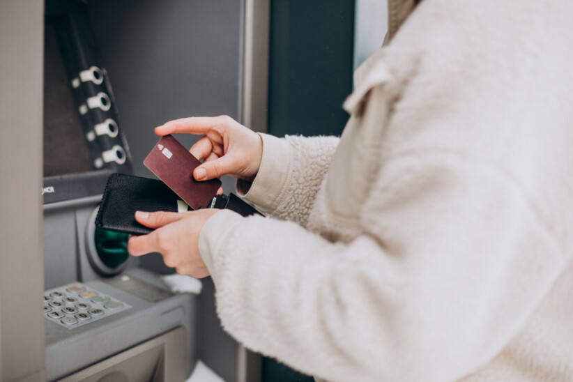 Osoba wypłacająca pieniądze z bankomatu przy użyciu karty płatniczej