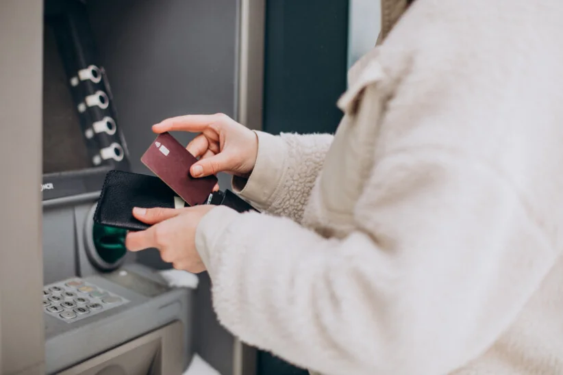 Osoba wypłacająca pieniądze z bankomatu przy użyciu karty płatniczej